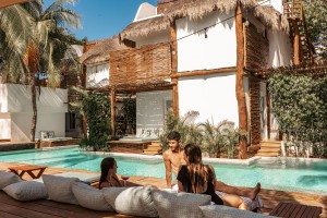 Group of friends relaxing by the swimming pool at Cabanas Tulum Beach Hotel & Spa, Mexico, enjoying their time.